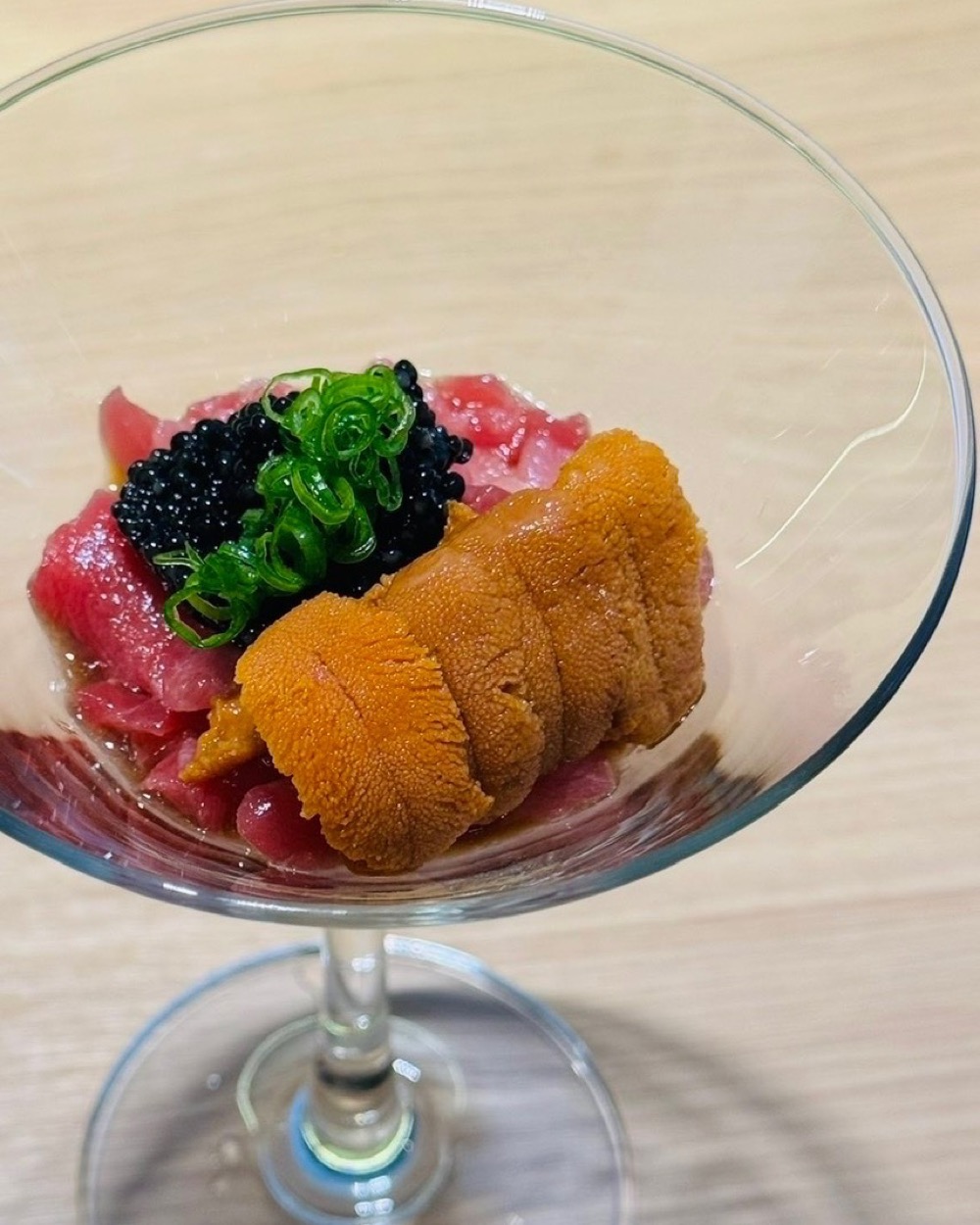 A martini glass of tuna, uni and caviar, topped with scallion.