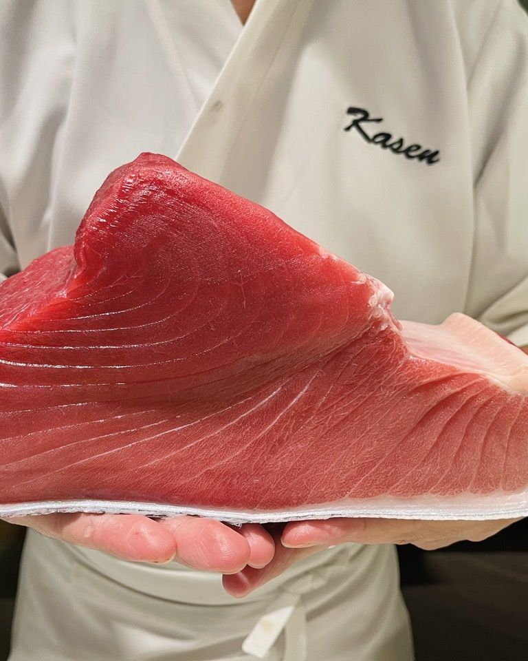 A chef in Kasen whites holding a full loin of tuna.