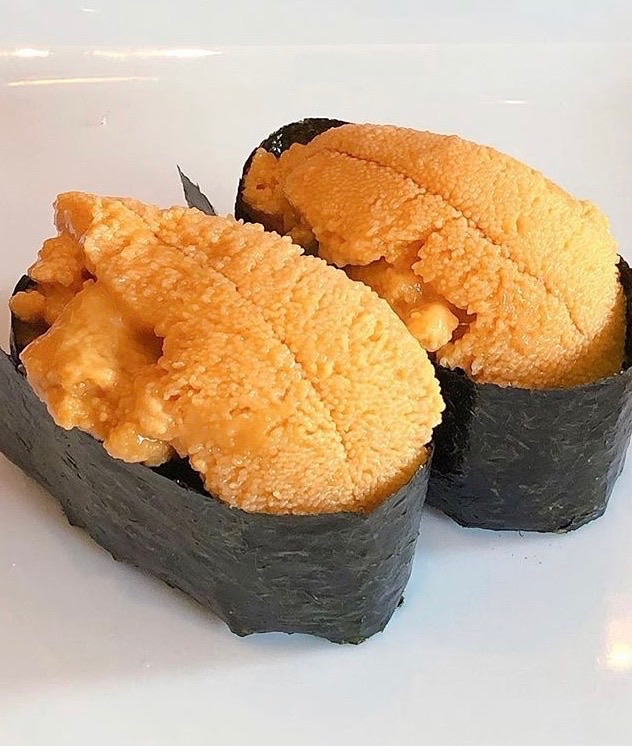 Two pieces of uni nigiri, whole sea urchin roe draped over rice and nori.