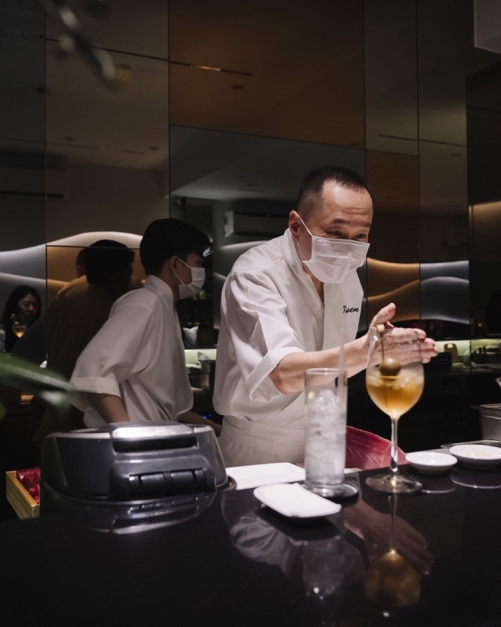 Kim Chu at the bar, preparing a drink, in Kasen whites.