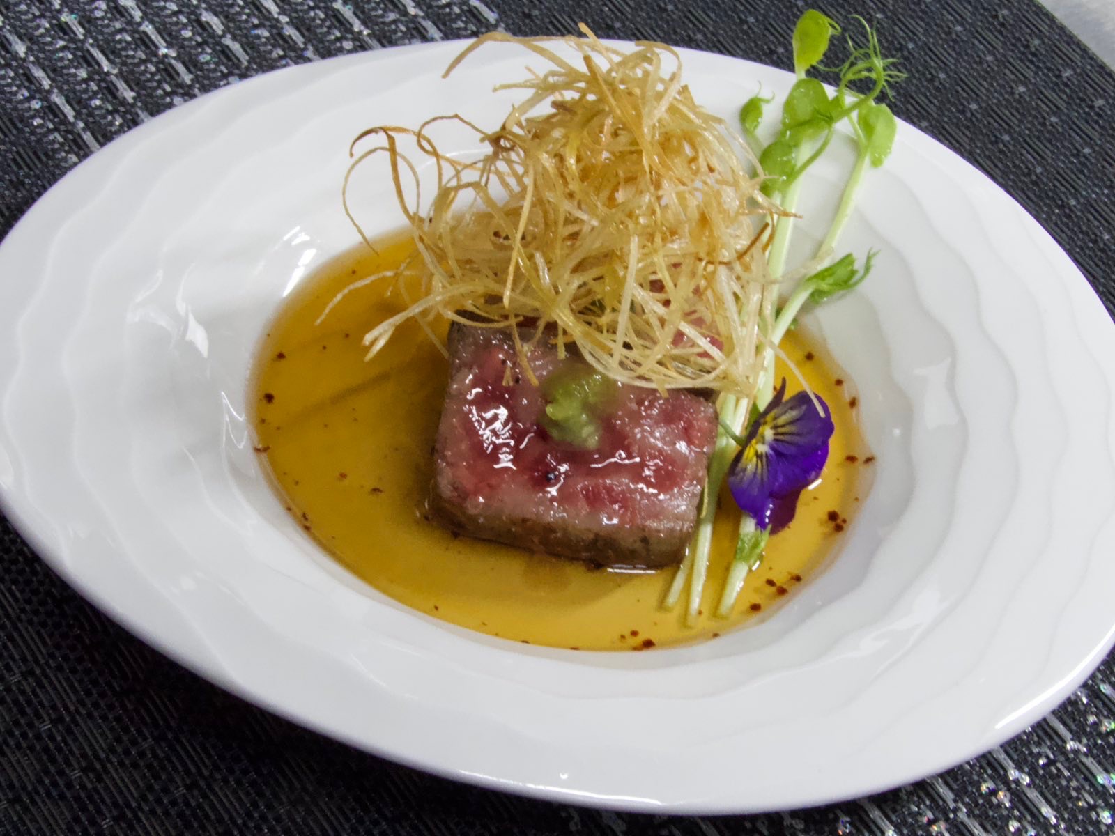 Beef served with crisp fried leeks and sauce.