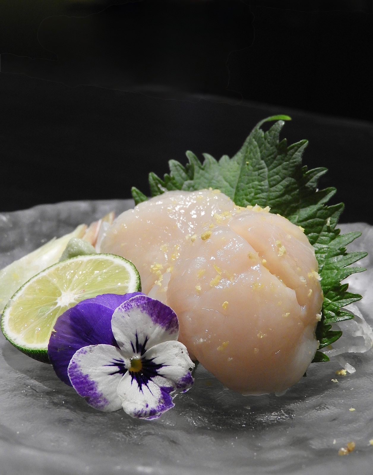 Scallop sashimi with lime, shiso and edible flowers.