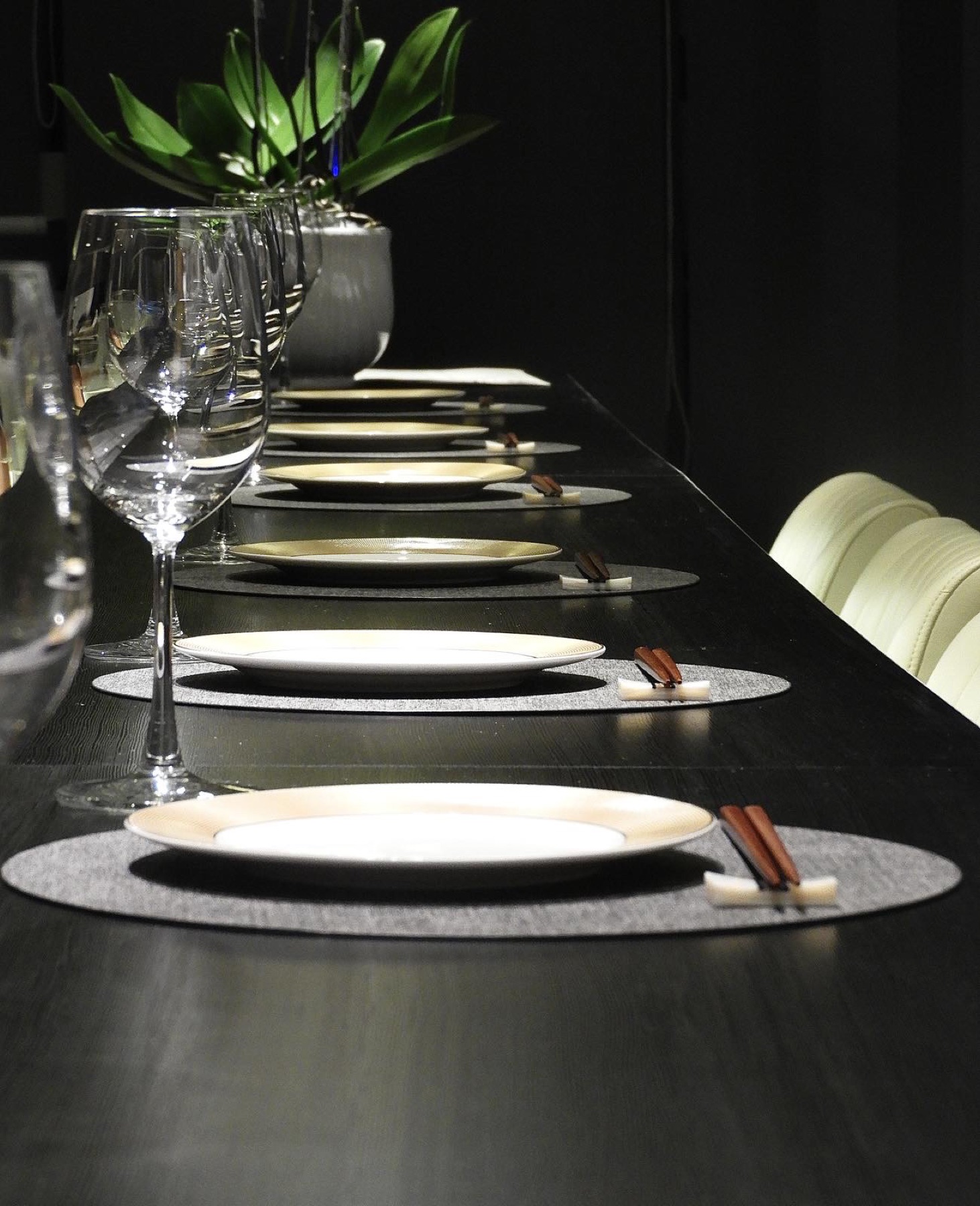 A row of place settings along Kasen's counter, wine glasses and orchids